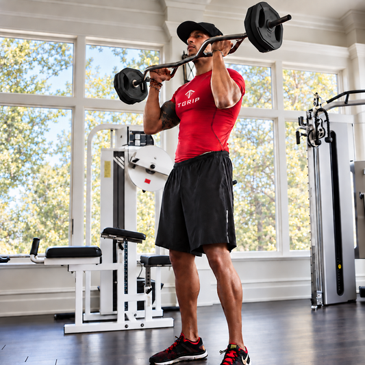 Athlete performing a standing curl with the Tgrip Shorty and black weight plates in a home gym